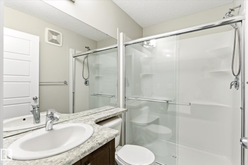 Bathroom featuring a glass-enclosed shower with sliding doors, a vanity with an oval sink and chrome faucet, and a stone-finish countertop - 9039 219 Street, Edmonton, AB 