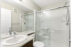 Bathroom featuring a glass-enclosed shower with sliding doors, a vanity with an oval sink and chrome faucet, and a stone-finish countertop - 