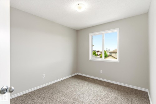 Room featuring light gray painted walls, a double-paned window, and textured carpet flooring - 9039 219 Street, Edmonton, AB 