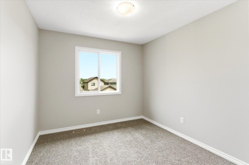 Interior room featuring light gray wall paint, white trim, and textured gray carpeting - 9039 219 Street, Edmonton, AB 