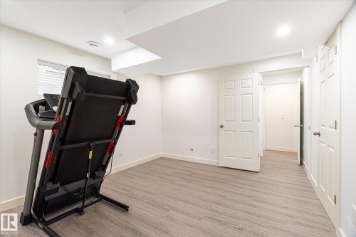 Versatile room featuring wood-finish flooring, recessed lighting, and white baseboards - 9039 219 Street, Edmonton, AB 