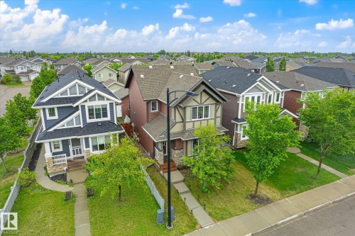 Residential street featuring a variety of distinct architectural styles, including a prominent blue home with stone facade accents and a gabled roof - 9039 219 Street, Edmonton, AB 