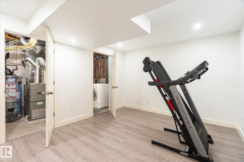 Finished basement space with wood-finish flooring, recessed lighting, and white baseboards - 9039 219 Street, Edmonton, AB 