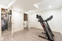 Finished basement space with wood-finish flooring, recessed lighting, and white baseboards - 