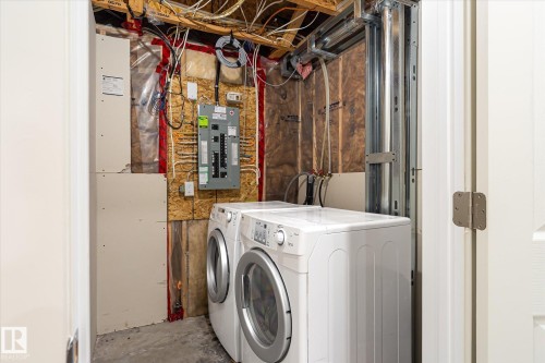 Dedicated laundry area with concrete flooring, exposed ceiling joists, and visible utility connections - 9039 219 Street, Edmonton, AB 