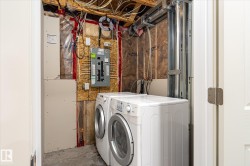 Dedicated laundry area with concrete flooring, exposed ceiling joists, and visible utility connections - 