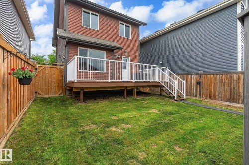 Rear exterior featuring a spacious wooden deck with white railings, steps to a grassy yard, and a full-height privacy fence - 9039 219 Street, Edmonton, AB 