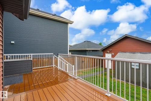 Outdoor deck featuring composite flooring, white railings, and a red siding exterior - 9039 219 Street, Edmonton, AB 