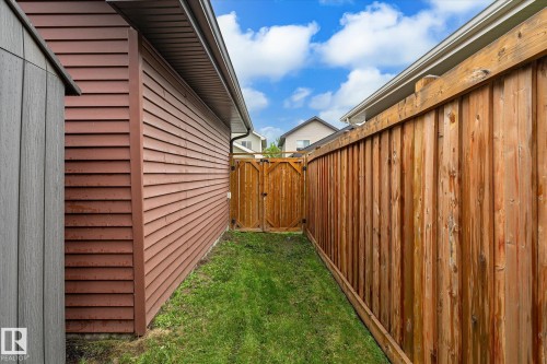 Private yard space featuring a stained wood privacy fence and a matching wood gate - 9039 219 Street, Edmonton, AB 