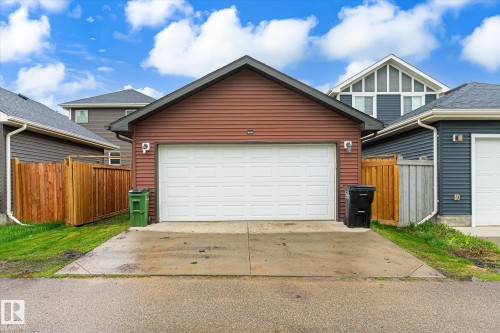 Detached garage with horizontal siding, a white sectional overhead door, and a concrete driveway - 9039 219 Street, Edmonton, AB 