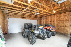 Spacious garage featuring exposed wood beam ceiling, concrete flooring, and a large white sectional garage door - 