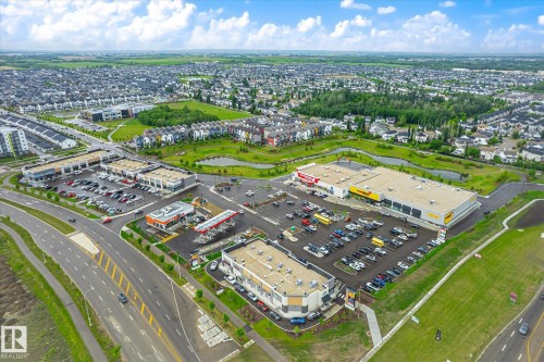 Aerial view of a commercial and residential area featuring multiple retail plazas, a gas station, a large grocery store, and extensive parking areas - 9039 219 Street, Edmonton, AB 