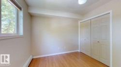 Room featuring light wood-finish flooring, neutral wall paint, and a large window with roller shades - 