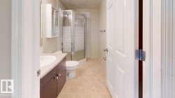 Bathroom featuring a shower enclosure with frosted glass, a vanity with a white countertop and wood-finish cabinetry, and a wall-mounted medicine cabinet - 