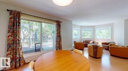 Open-concept living area featuring wood-finish flooring, a contemporary ceiling light fixture, and a bay window configuration - 