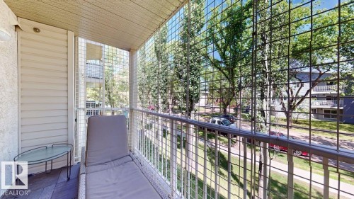 Balcony area featuring wood-finish flooring, a white metal railing, and a slatted exterior wall - 201 11408 108 Avenue, Edmonton, AB 