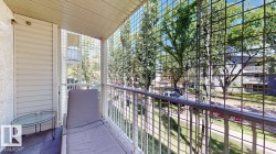Balcony area featuring wood-finish flooring, a white metal railing, and a slatted exterior wall - 