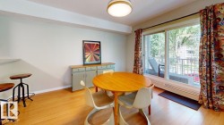 Light wood-finish flooring, white walls, and a large sliding glass door opening to an outdoor patio space - 