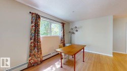 Bright room featuring wood-finish flooring, light-colored walls, and a large window with white trim - 