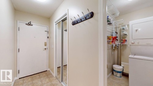 Entryway featuring tile flooring, a mirrored closet with sliding doors, and a coat rack - 201 11408 108 Avenue, Edmonton, AB 