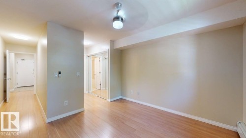 Open-concept room featuring wood-finish flooring, light neutral wall paint, and a semi-flush ceiling light fixture - 201 11408 108 Avenue, Edmonton, AB 