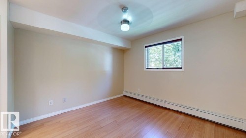 Spacious room featuring wood-finish flooring and neutral wall tones - 201 11408 108 Avenue, Edmonton, AB 