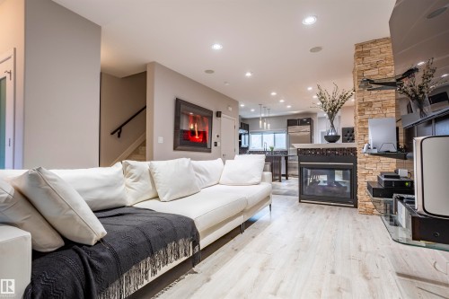 Open-concept living space featuring light wood-finish flooring, recessed lighting, and a stone-clad fireplace - 4949 Terwillegar Common, Edmonton, AB 