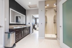 Contemporary bathroom featuring a dual vanity with dark wood cabinetry and a light-up mirror - 