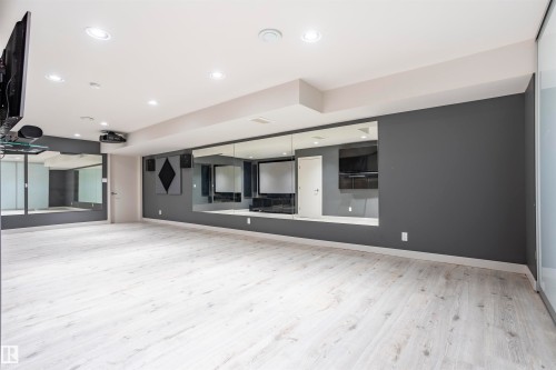 Open concept room featuring light wood-finish flooring, recessed lighting, and a mirrored wall - 4949 Terwillegar Common, Edmonton, AB 