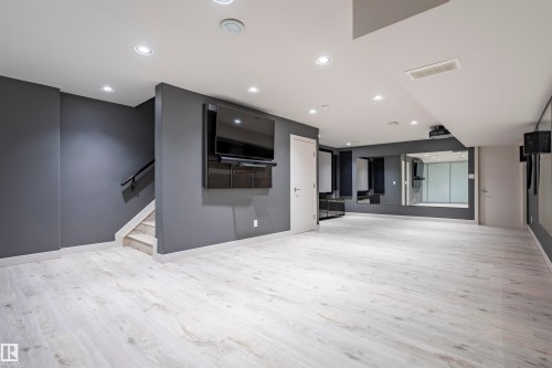 Spacious room featuring light wood-finish flooring, recessed lighting, and a wall-mounted media console - 4949 Terwillegar Common, Edmonton, AB 