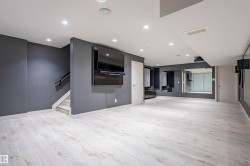 Spacious room featuring light wood-finish flooring, recessed lighting, and a wall-mounted media console - 