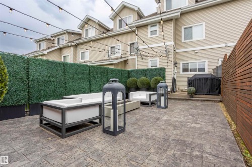 Expansive private patio featuring stamped concrete flooring, a horizontal slat wood fence, and a faux hedge privacy screen - 4949 Terwillegar Common, Edmonton, AB 