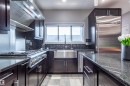 Modern kitchen featuring dark wood cabinetry, stainless steel appliances, and granite countertops - 4949 Terwillegar Common, Edmonton, AB 