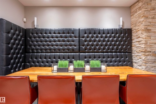Dining area featuring a built-in tufted banquette, a solid wood-finish table, and a stacked stone accent wall - 4949 Terwillegar Common, Edmonton, AB 