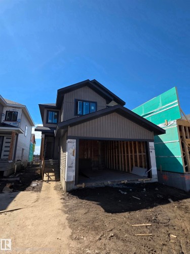 Two-story exterior with brown and dark gray siding, black trimmed windows, a single-car garage opening, and a concrete foundation - 13123 187 Avenue, Edmonton, AB 
