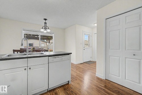Kitchen island with integrated double basin sink and a chrome pull-down faucet - 710 Glenwright Court, Edmonton, AB 