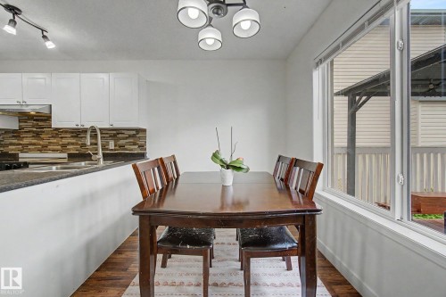 Dining area featuring wood-finish flooring, a contemporary ceiling light fixture, and a large window - 710 Glenwright Court, Edmonton, AB 