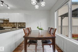 Dining area featuring wood-finish flooring, a contemporary ceiling light fixture, and a large window - 
