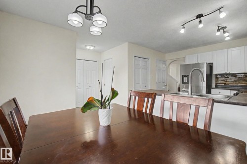 Dining area with dark wood-finish table, overhead chandelier, and direct sightline to the kitchen - 710 Glenwright Court, Edmonton, AB 