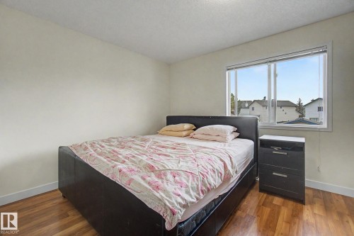 Bright room featuring wood-finish flooring, a large window, white walls, and white baseboards - 710 Glenwright Court, Edmonton, AB 
