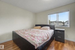 Bright room featuring wood-finish flooring, a large window, white walls, and white baseboards - 