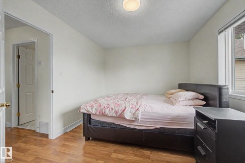 Bedroom with wood-finish flooring, white walls, and a window with white trim - 710 Glenwright Court, Edmonton, AB 