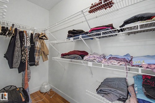 Walk-in closet featuring white wire shelving, multiple hanging rods, and wood-finish flooring - 710 Glenwright Court, Edmonton, AB 