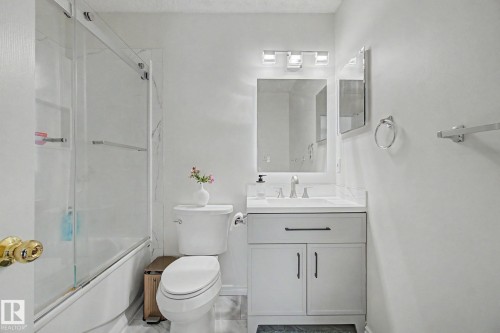 Bathroom featuring a single vanity with a white countertop and white cabinetry, a rectangular mirror, and a three-light vanity fixture - 710 Glenwright Court, Edmonton, AB 