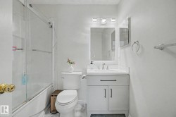 Bathroom featuring a single vanity with a white countertop and white cabinetry, a rectangular mirror, and a three-light vanity fixture - 