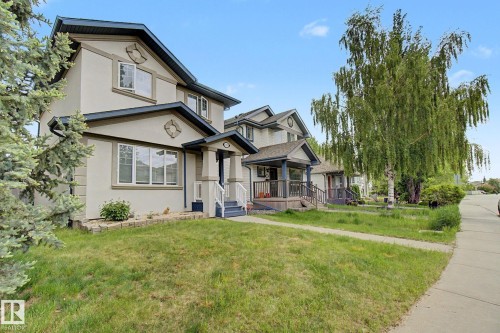 Stucco exterior with contrasting trim, gable rooflines, covered front porch with white railings, and mature landscaping - 710 Glenwright Court, Edmonton, AB 