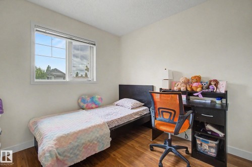 Bedroom featuring wood-finish flooring, a white-framed window, and neutral wall paint - 710 Glenwright Court, Edmonton, AB 
