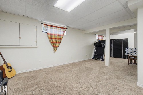 Carpeted room featuring a drop ceiling with recessed lighting, white walls, and built-in storage cabinetry - 710 Glenwright Court, Edmonton, AB 