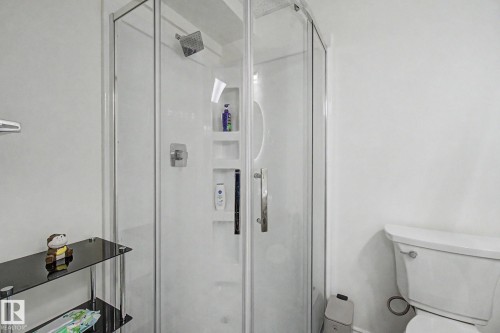 Corner shower enclosure featuring clear glass panels and a chrome-finish shower head - 710 Glenwright Court, Edmonton, AB 