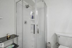 Corner shower enclosure featuring clear glass panels and a chrome-finish shower head - 